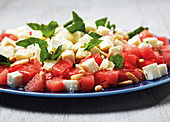 Watermelon with feta cheese, honey and pine nuts