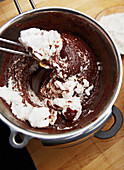 Beaten egg whites being folded into chocolate cake mixture