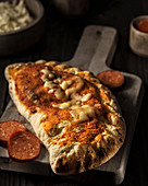 Closed pizza 'Calzone' with pepperoni sausage