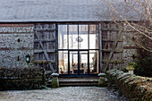 Vast glass doors and timber shutters at exterior of barn conversion
