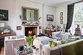 Elegant drawing room with chairs and sofa from, linen covers and a zebra photography to the right of the fireplace