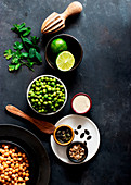 Chickpeas and green peas placed on a bowl near crackers on dark background