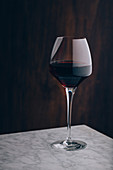 Crystal classic glass of red wine placed on marble table on black background