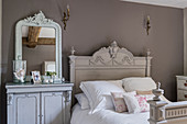 Carved wooden bed and cabinet with decorative mirror in restored 16th century farmhouse