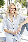 Blonde Frau in hellblau gestreiftem Hemd und Jeans