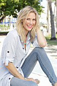 A blonde woman wearing a light-blue striped shirt and jeans