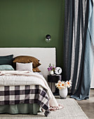 Double bed with upholstered headboard in front of green wall
