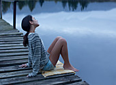 Serene woman sitting on dock over lake