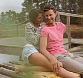 Smiling couple sitting on dock over lake