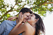 Smiling couple hugging under tree