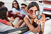 Woman taking picture from convertible