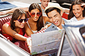 Friends reading road map in convertible