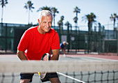 Older man playing tennis on court