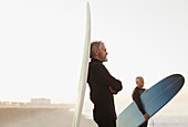 Older surfer leaning on board on beach