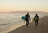 Older surfers carrying boards on beach