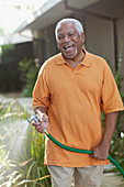 Older men watering plants in backyard