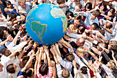 Crowd of people reaching for globe