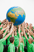 Team in green t-shirts reaching for globe