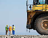 Workers talking with machinery in quarry