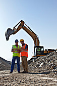 Workers talking by digger in quarry