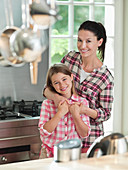 Woman hugging daughter in kitchen