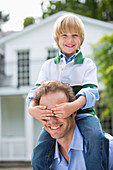 Boy covering father's eyes outdoors