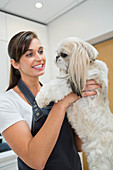 Groomer holding dog in office