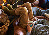 Boy drinking cup of coffee by fire
