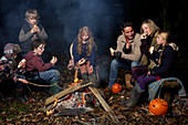 Family eating around campfire at night
