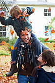 Father and son playing in autumn leaves