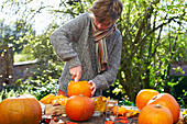 Teenage boy carving pumpkins outdoors