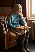 Girl reading book in armchair