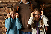 Girls using leaves as antlers with father
