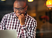 Smiling man reading laptop indoors