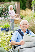Older man in wheelchair reading newspaper