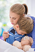 Mother hugging sick son in bed