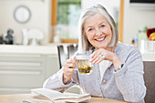 Older woman drinking tea and reading