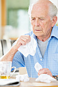 Older man with cold wiping his nose