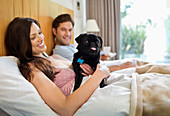 Couple relaxing with dog in bed