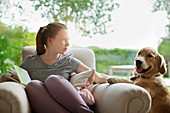 Girl relaxing with dog in armchair