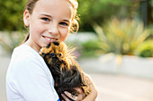 Smiling girl holding guinea pig outdoors