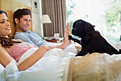 Woman teaching dog 'high five' in bed