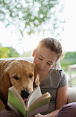 Girl reading with dog in armchair