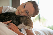 Girl petting cat on bed