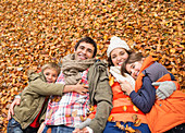 Smiling family laying in autumn leaves