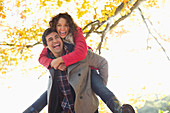 Man carrying girlfriend piggyback in park