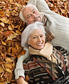 Older couple laying in autumn leaves