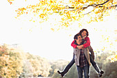 Man carrying girlfriend piggyback in park