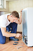 Repairman working on appliance in kitchen