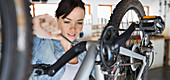 Woman working on bicycle in shop